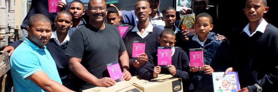 Die enorme vrag boeke wat deur Jack Doyle van Engeland per vragskip na Gansbaai PrimÃªr gestuur is, met Tommy Volkwyn (skoolhoof) direk agter een van die kartondose